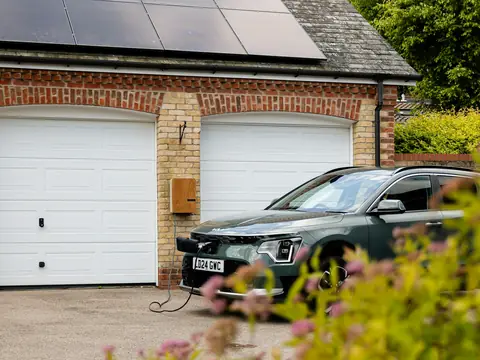 Villa med solpaneler på garagetaket och en bil på uppfarten